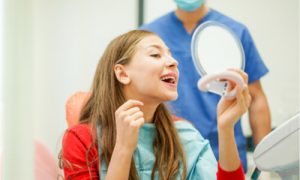 The woman asks the dentist how much does professional teeth whitening cost.