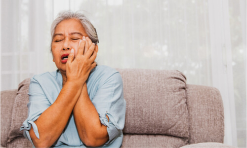 An elderly woman experiencing severe toothache, associated with swelling.